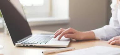 otwarty laptop i dłonie osoby obsługującej go
